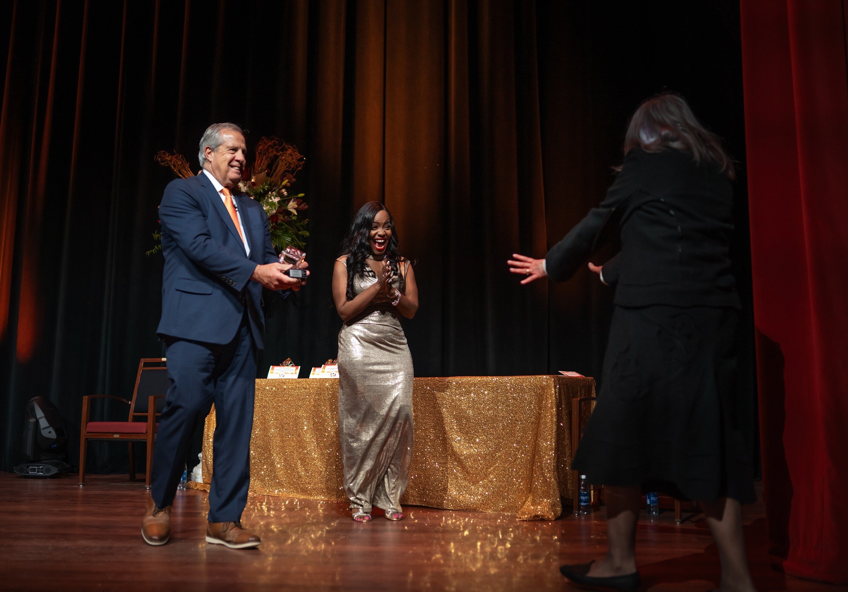 Tim Herman and Amari Steward present an honoree with an award in 2023