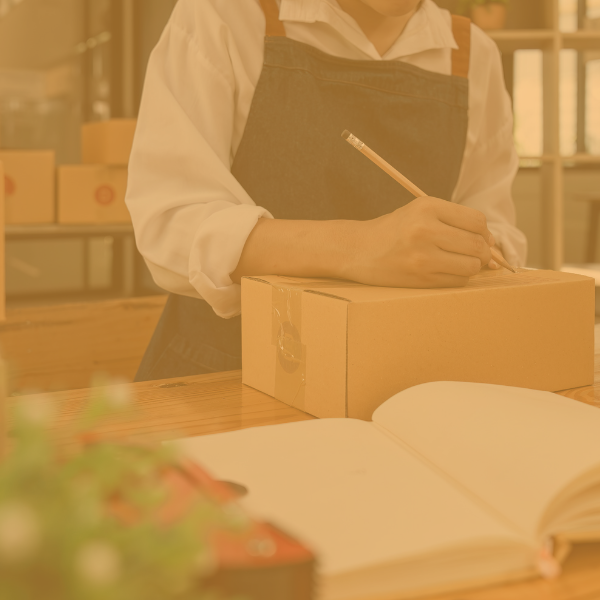 Small business person in an apron packing up an online order.