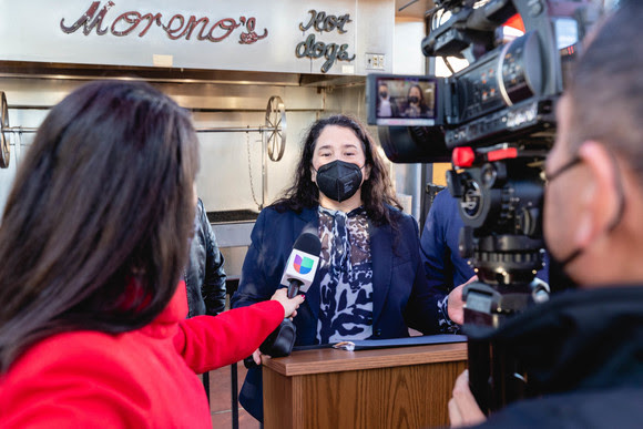 Photo of Administrator Guzman with a reporter and camera person.