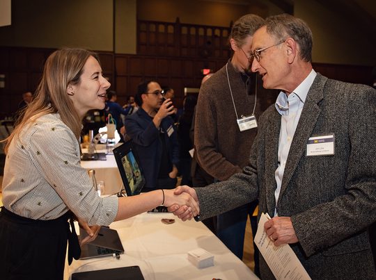 Photo so a woman and a man shaking hands over a table.